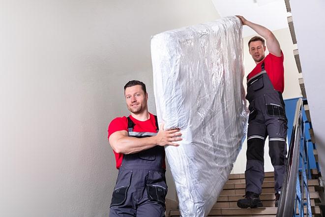 team of workers lifting a box spring out of a house in Bunker Hill